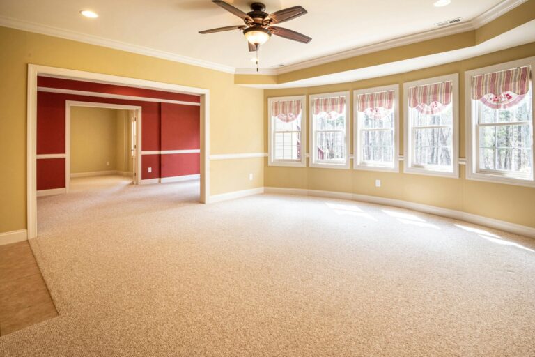 Bright and airy living room featuring large windows and a ceiling fan